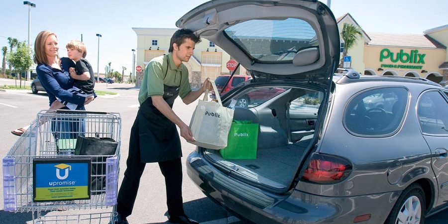 A publix bagger helps a mom load her groceries into her car